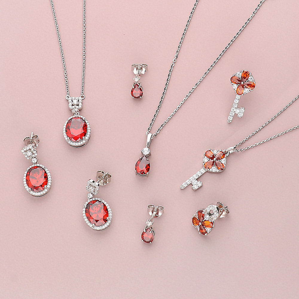 Flatlay view of Key and Lock CZ Stud Earrings in Sterling Silver, Red Color
