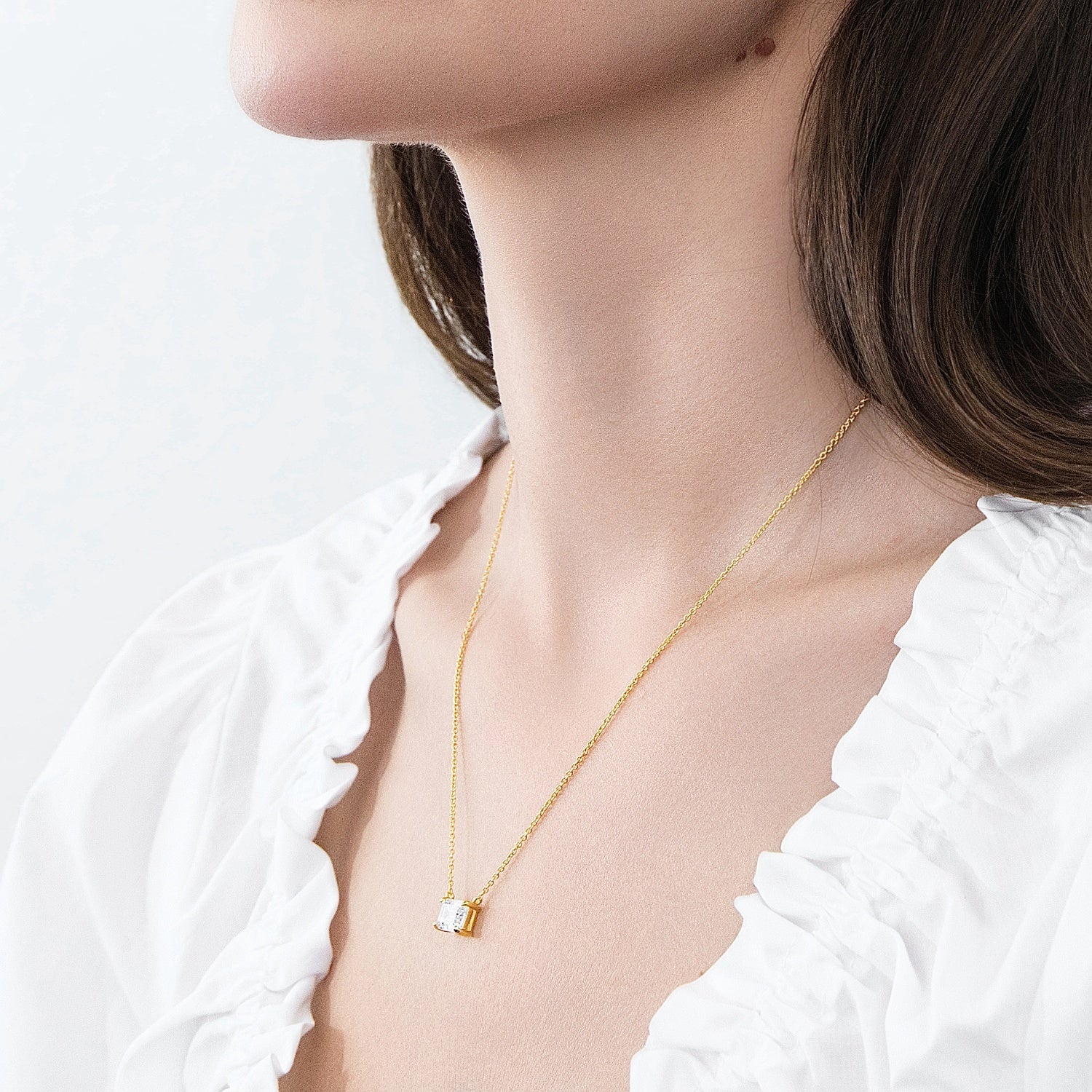 Model wearing Solitaire East-West Emerald Cut CZ Necklace in Sterling Silver, Gold Flashed