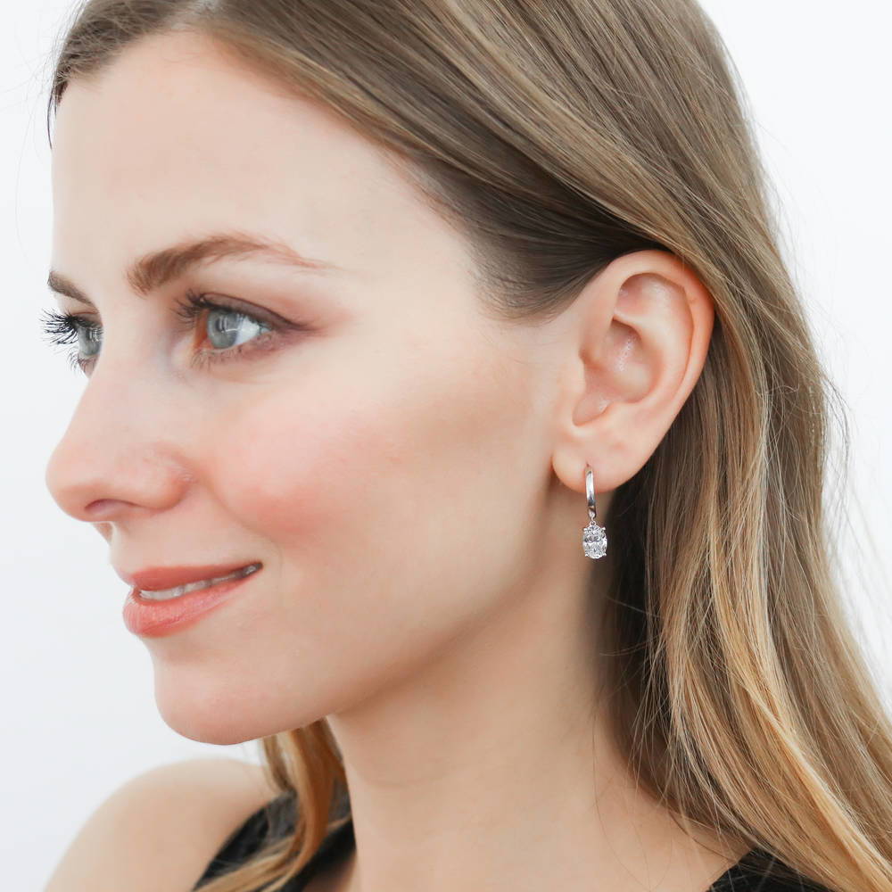 Model wearing Solitaire CZ Cartilage Huggie Earrings in Sterling Silver 0.5 inch, Rhodium Plated / Oval Cut