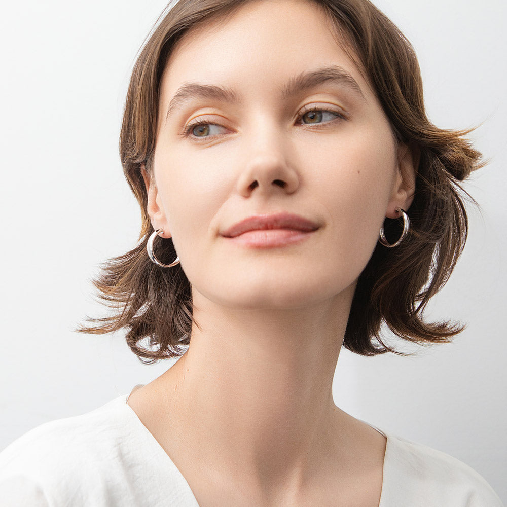 Model wearing Dome Small Hoop Earrings in Sterling Silver 1 inch, Rhodium Plated