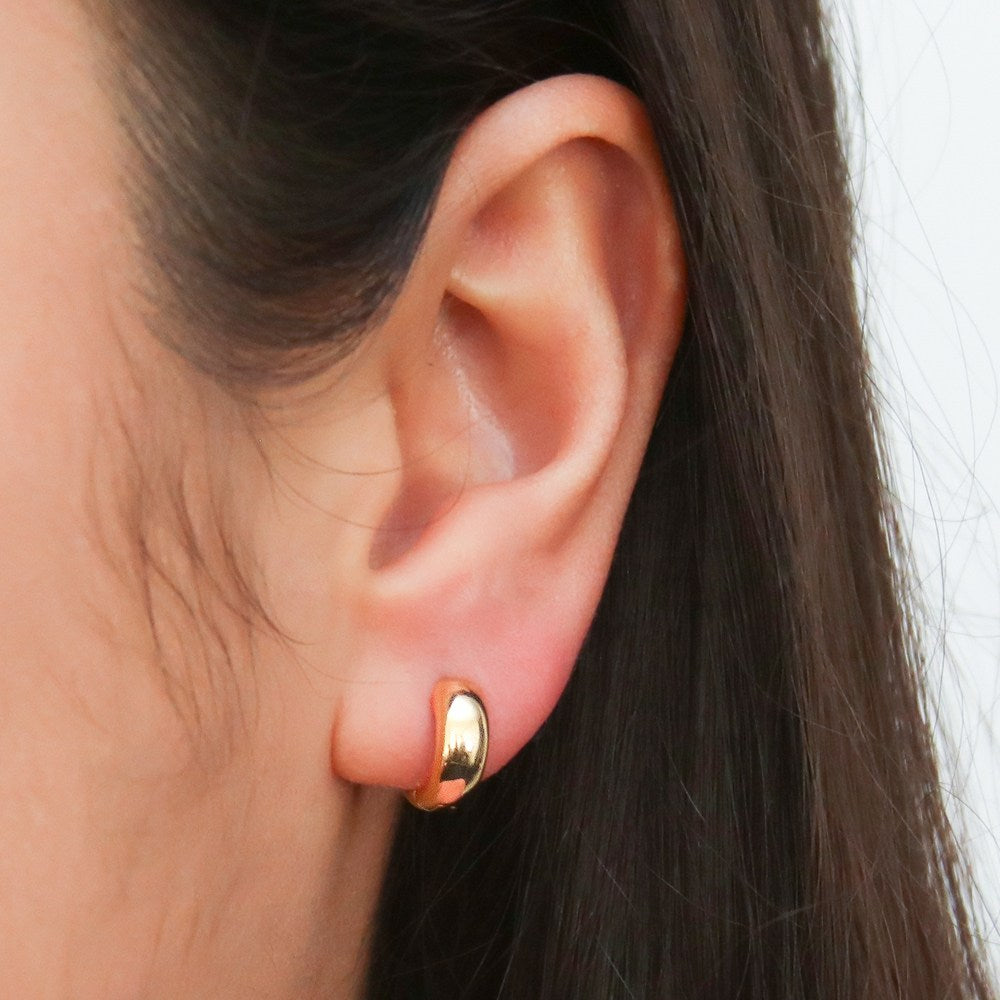 Model wearing Dome Mini Huggie Earrings in Sterling Silver 0.5 inch, Yellow Gold Flashed