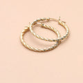 Flatlay view of Cable Medium Hoop Earrings in Sterling Silver 1.2 inch, Yellow Gold Flashed