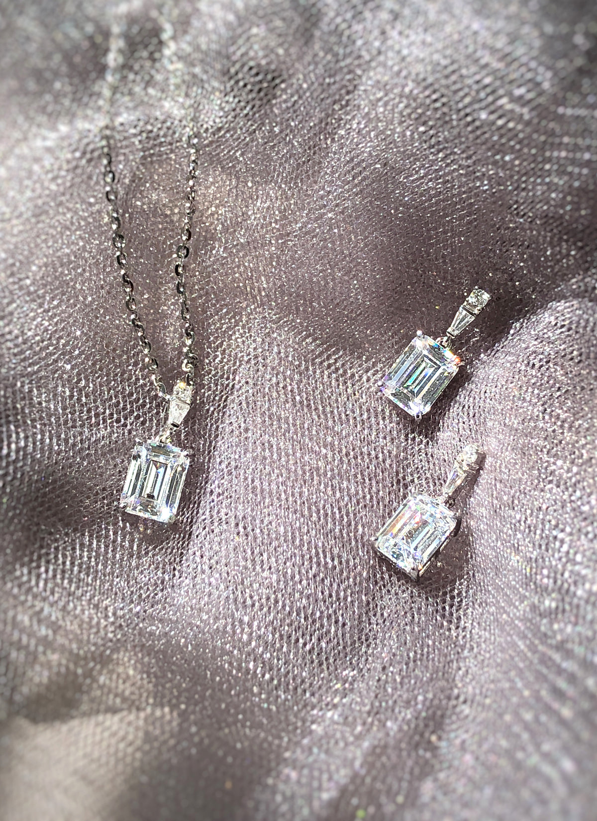 emerald cut necklace and earrings on a mesh background