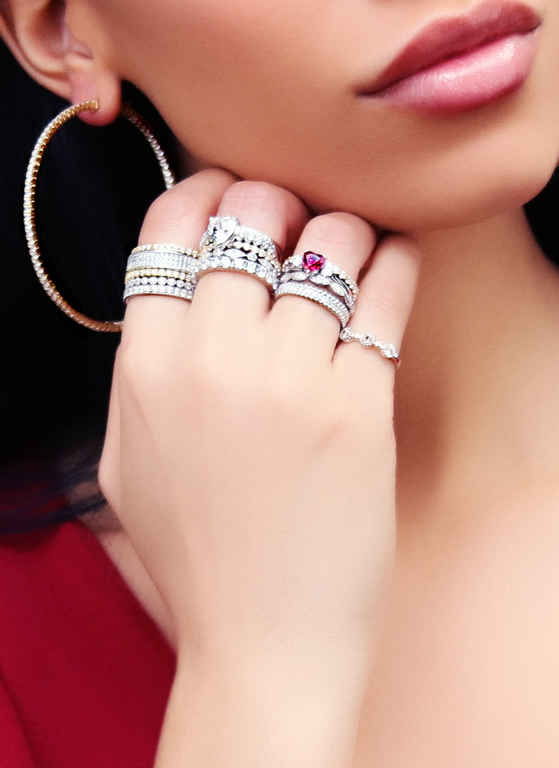 Model wearing stack of rings and hoop earrings.