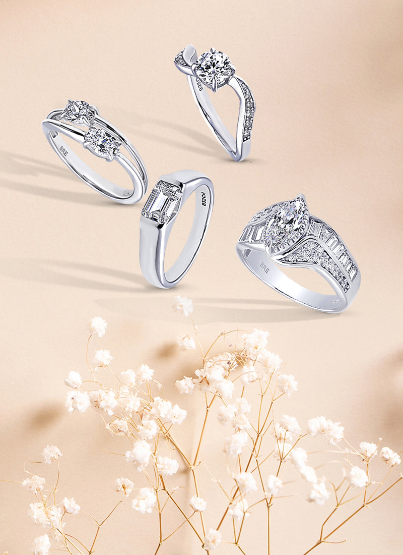 assorted silver engagement rings on cream color background with flowers.