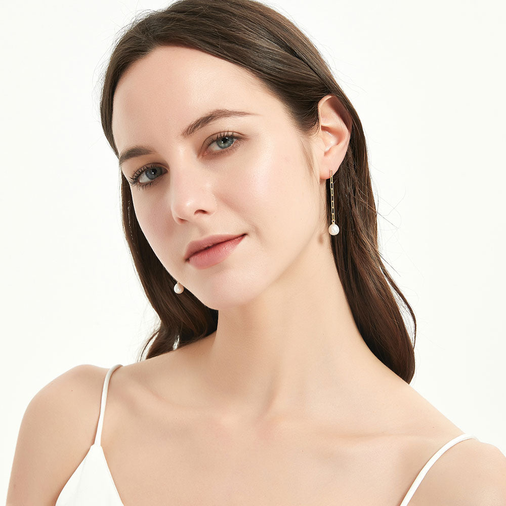 Model wearing Solitaire Oval Cultured Pearl Earrings in Sterling Silver, Yellow Gold Flashed