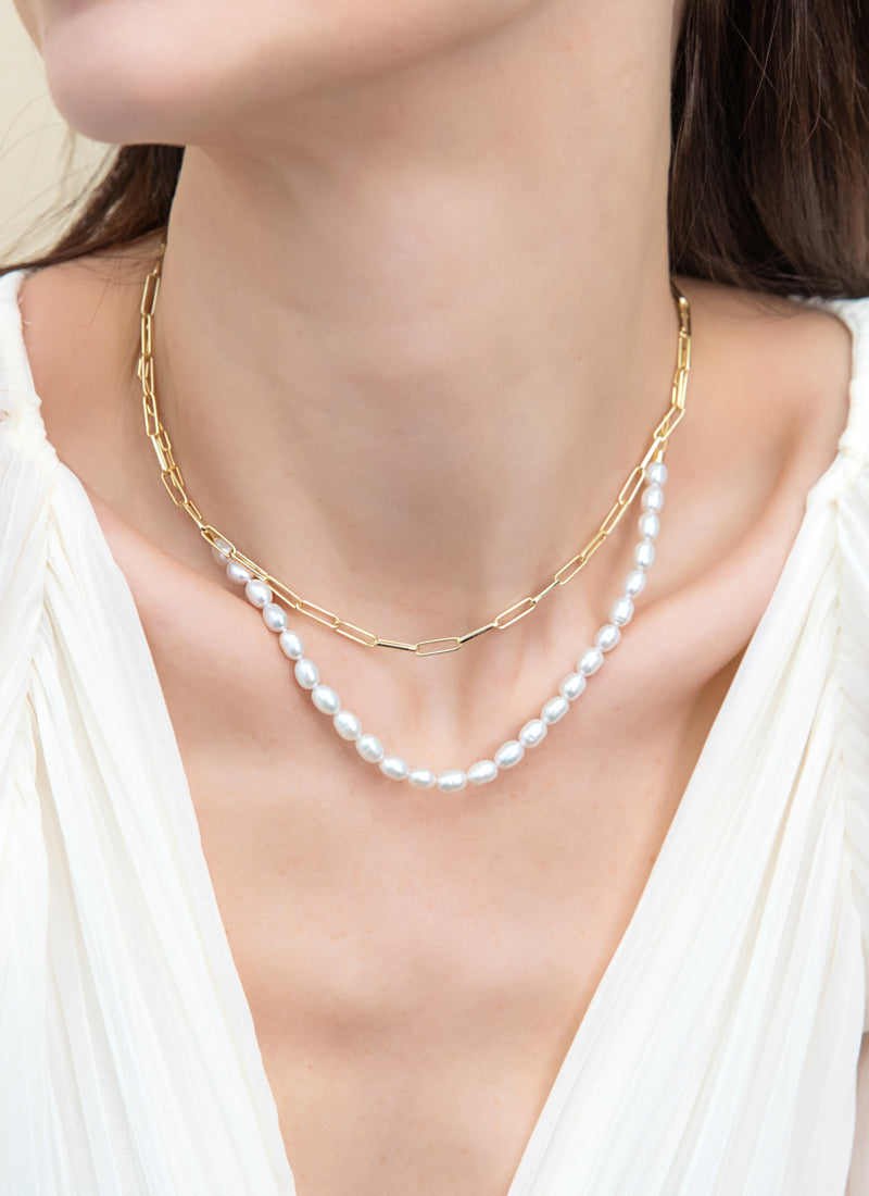 Model wearing pearl necklace and gold flashed paperclip chain.