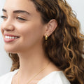 Model wearing Oval Dome Small Huggie Earrings in Sterling Silver 0.6 inch, Yellow Gold Flashed