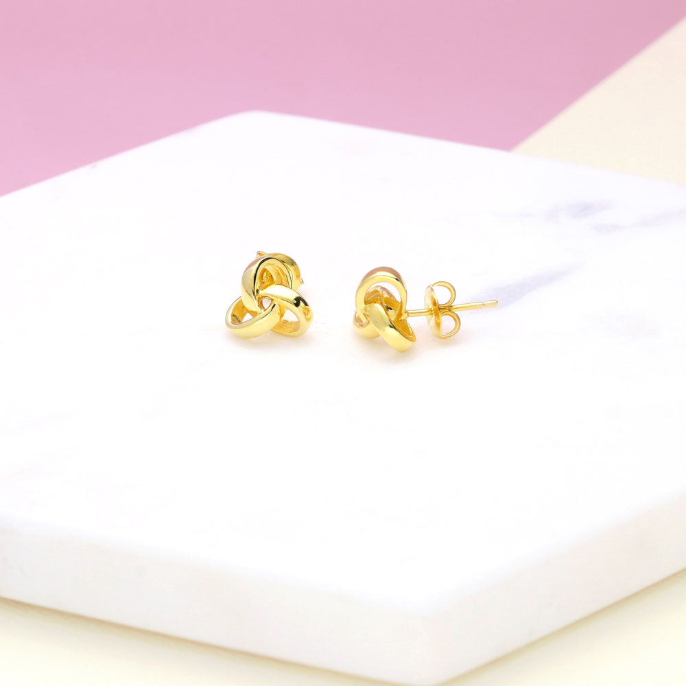 Flatlay view of Love Knot Stud Earrings in Sterling Silver, Yellow Gold Flashed