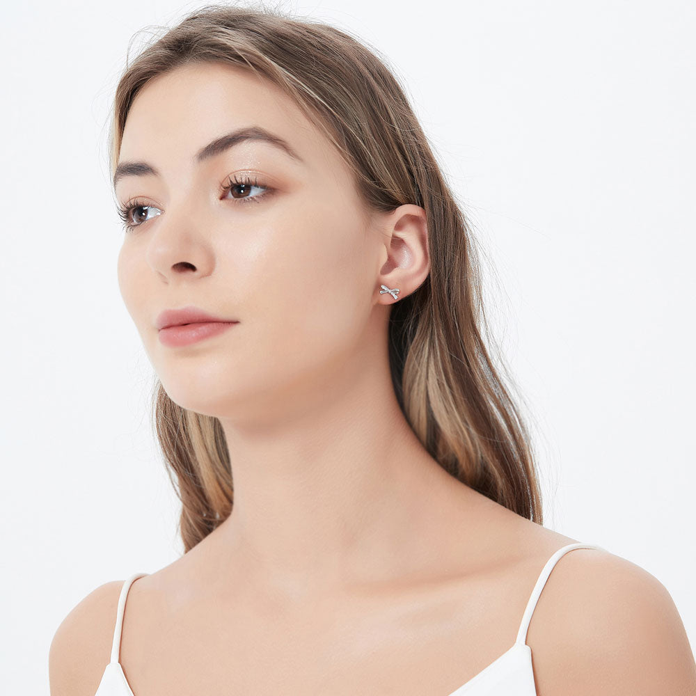 Model wearing Bow Tie Ribbon CZ Cartilage Stud Earrings in Sterling Silver, 3 of 5